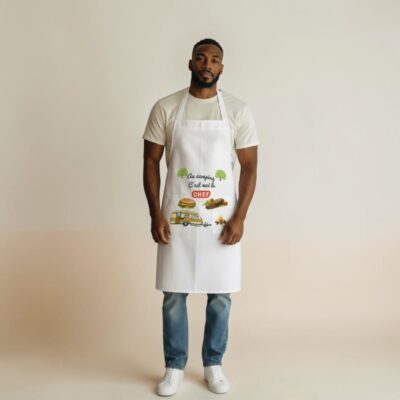 Tablier “Au camping c’est moi le chef” présenté sur mannequin, création artisanale BrikarDesign